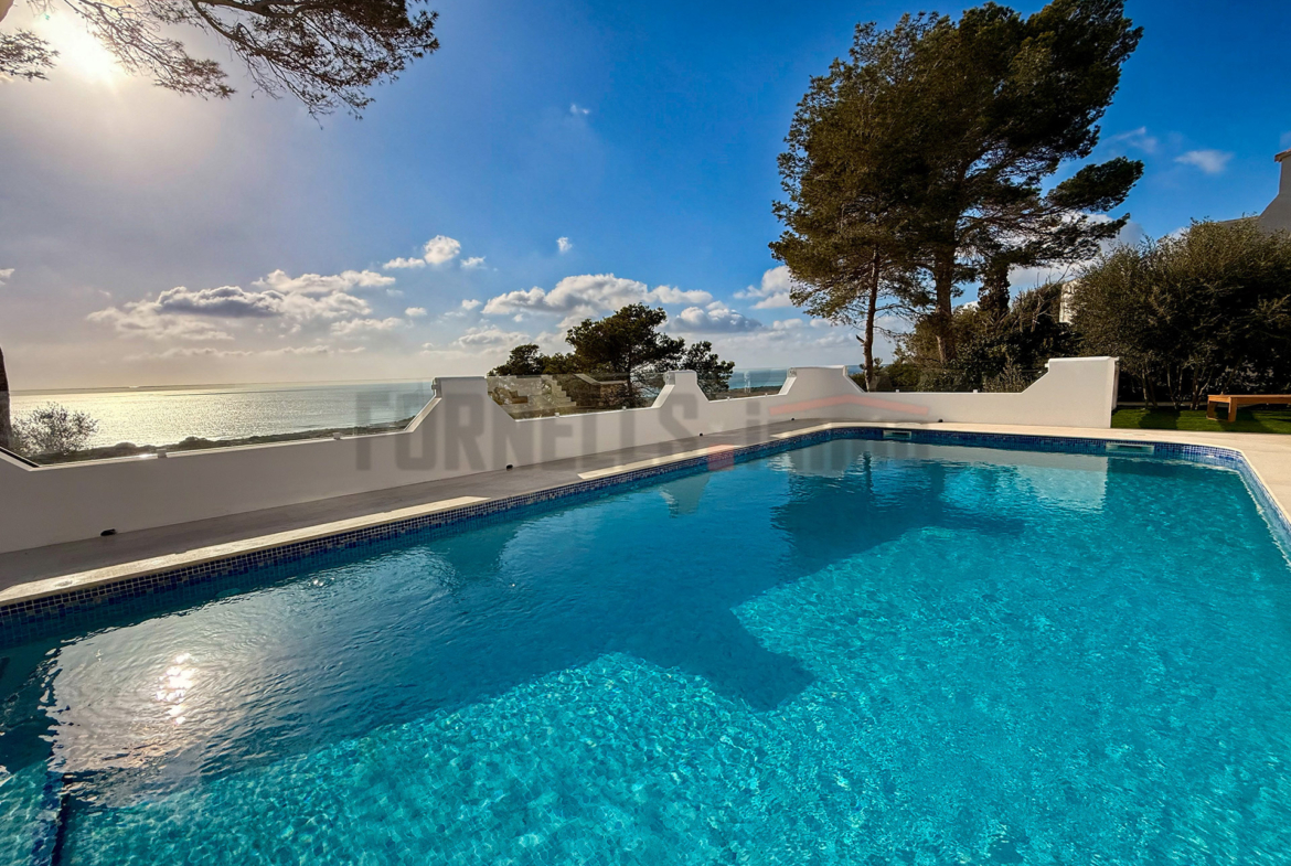 Piscina de aguas cristalinas con vistas panorámicas al mar Mediterráneo y cielo azul, en villa de lujo en Menorca.