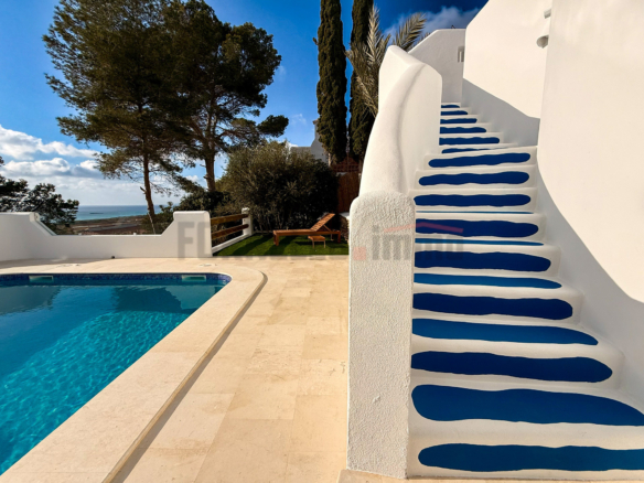 Escaleras blancas con escalones azules vibrantes y piscina con vistas al mar en una villa de lujo en Menorca