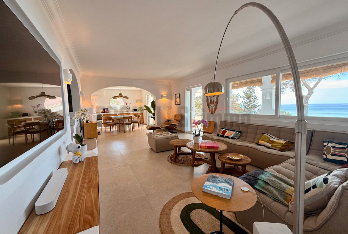 Salón espacioso con sofás, mesas de centro, televisión y vistas al mar en una villa de lujo en Menorca.