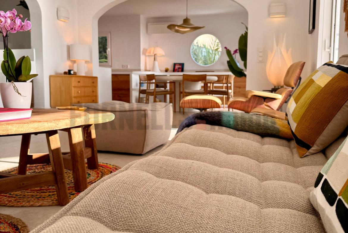 Sofá cómodo en salón de diseño, con mesas de centro y vista a comedor en villa de lujo en Menorca.
