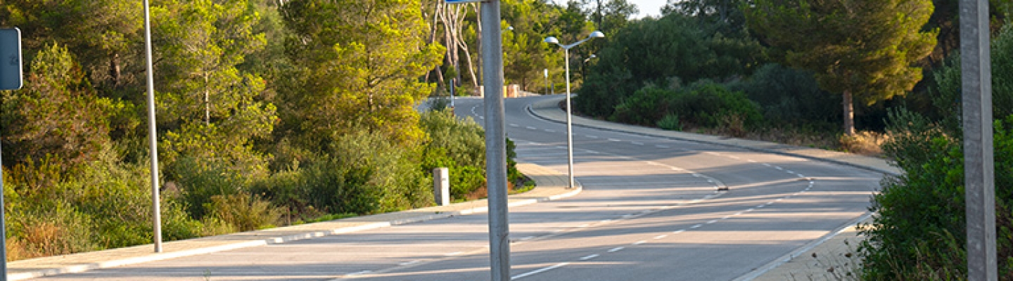 Calle bien mantenida en la urbanización Son Parc, Menorca, con aceras nuevas y farolas.